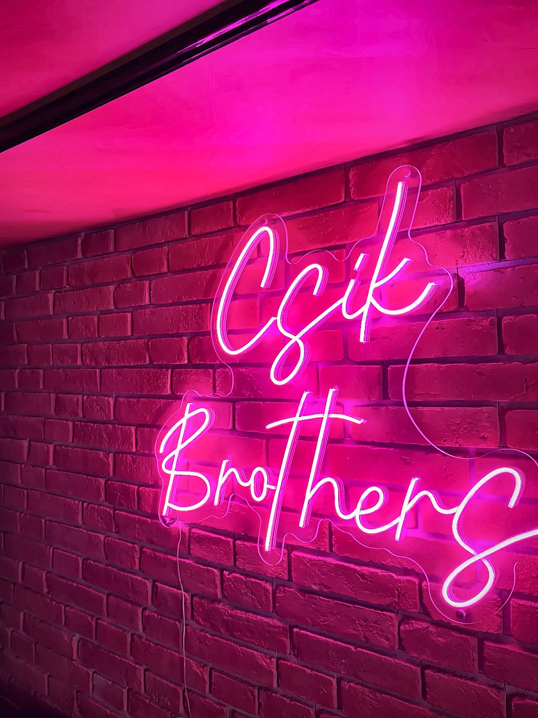 A Csík Brothers neon felirat a szalon téglafalán